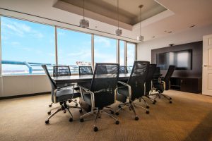 Photo of the Evans Philp board room with table surrounded by 10 chairs, three lights hanging from the ceiling, a large TV on the far wall and a wall of bright windows overlooking the city from the 16th floor.